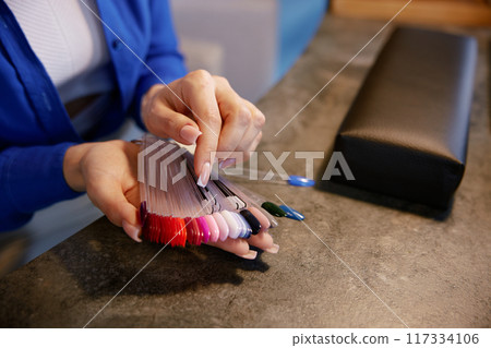 Woman client choosing color for manicure on nail polish coating palette Woman client choosing color for manicure on nail polish coating palette 117334106