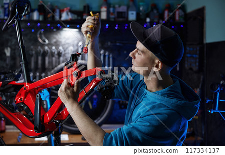 Repairman filling brake fluid working at bicycle workshop 117334137