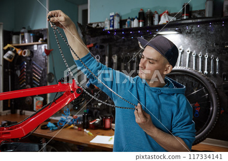 Professional male mechanic engaged in bicycle chain removal 117334141