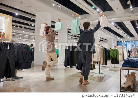 Excited female friends celebrating good shopping day Excited female friends celebrating good shopping day 117334154