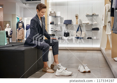 Young woman customer selecting new comfort trendy shoes at footwear boutique 117334197