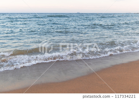 Soft ocean wave on clean sandy beach background. 117334221