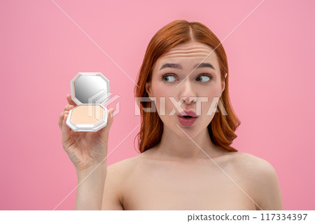Ginger woman with bare shoulders with cream powder in hands Ginger woman with bare shoulders with cream powder in hands 117334397