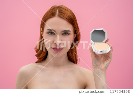 Ginger woman with bare shoulders with cream powder in hands 117334398