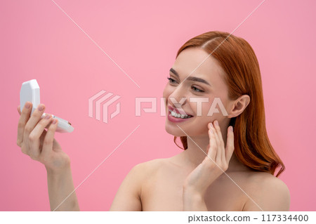 Portrait of a smiling cute young woman with face powder in hands 117334400
