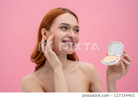 Portrait of a smiling cute young woman with face powder in hands 117334401