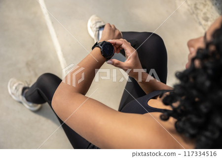 Top view of a smiling pretty woman in sportswear checking her pulsometer 117334516