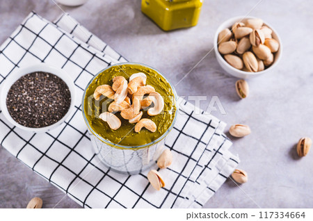 Chia seeds with yogurt, pistachio spread and cashew nuts in a glass on a table Chia seeds with yogurt, pistachio spread and cashew nuts in a glass on a table 117334664