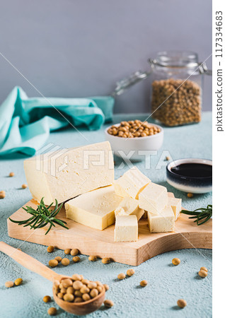 Fresh slices of soy cheese tofu and rosemary on a wooden board on the table vertical view 117334683
