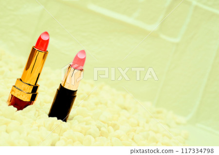 Two red pink cosmetic lipsticks on yellow lime 117334798