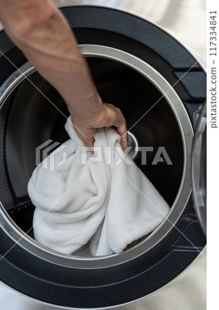 Unrecognizable man operating using washing machine at commercial laundry Unrecognizable man operating using washing machine at commercial laundry 117334841