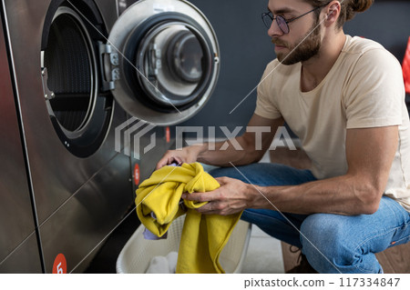 Caucasian woman handling housework chores doing laundry at public laundromat 117334847