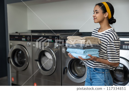 Woman housewife holding folded towels at self-service laundry 117334851