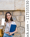 smiling student with a backpack showing a smartphone with white background 117335530
