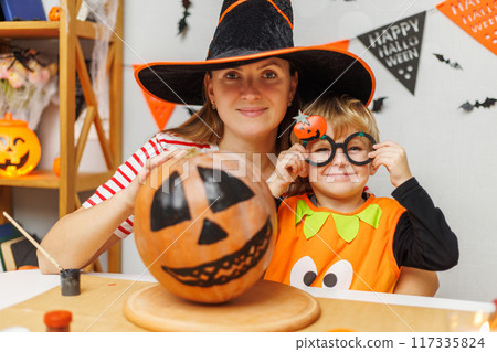 Family decorating Halloween pumpkin together Family decorating Halloween pumpkin together 117335824
