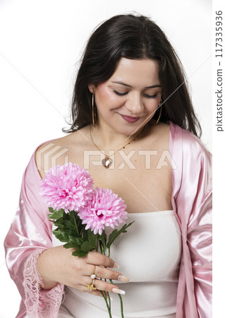 Curvy girl posing with a white dress and some flowers in her hand 117335936