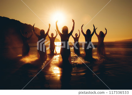 group of people practicing yoga and meditation at sunset on sunny beach, silhouette of women group of people practicing yoga and meditation at sunset on sunny beach, silhouette of women 117336533