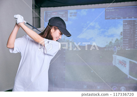 一名女子在室內高爾夫練習場練習 一名女子在室內高爾夫練習場練習 117336720
