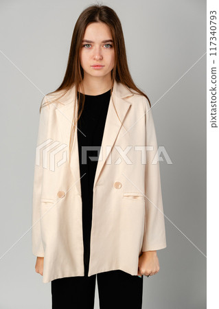 Young Woman in White Jacket and Black Pants on Gray Background. Young Woman in White Jacket and Black Pants on Gray Background. 117340793