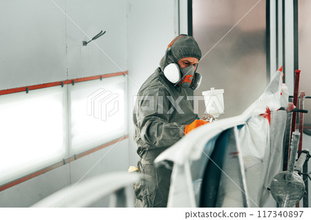 Auto painter painting a car with vaporizer gun inside a paint booth 117340897