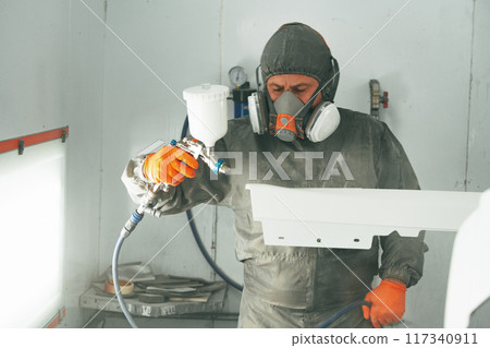Auto painter painting a car with vaporizer gun inside a paint booth Auto painter painting a car with vaporizer gun inside a paint booth 117340911