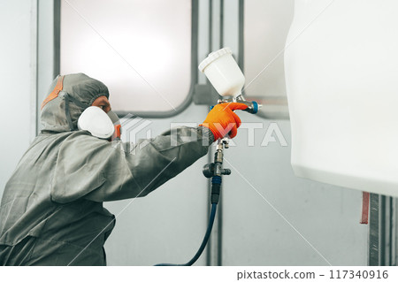 Auto painter painting a car with vaporizer gun inside a paint booth Auto painter painting a car with vaporizer gun inside a paint booth 117340916