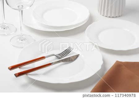 Stylish table setting with white dishware on white tablecloth 117340978