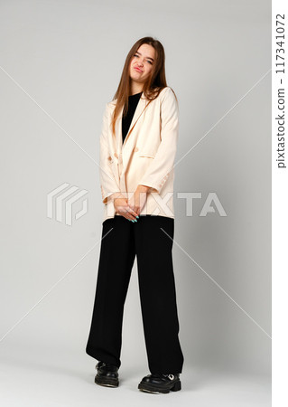 Young Woman Making a Playful Face Against a Gray Background in a Studio 117341072