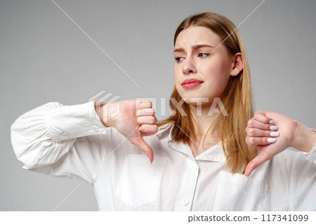 Young Woman in White Shirt Pointing Finger Down Dislike 117341099