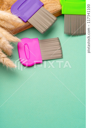 Three combs for lice removing on green background 117341100