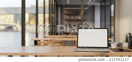 A laptop mockup on a wooden table in a cafe seating area or in a co-working space in an office. A laptop mockup on a wooden table in a cafe seating area or in a co-working space in an office. 117341217