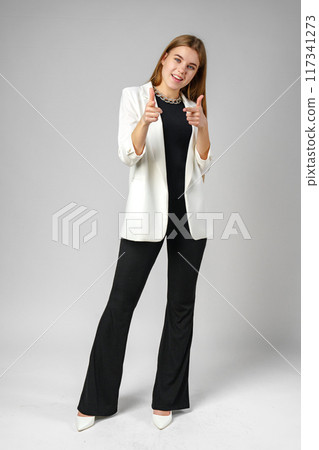 Young Woman in White Blazer Pointing at You Against a Grey Background 117341273