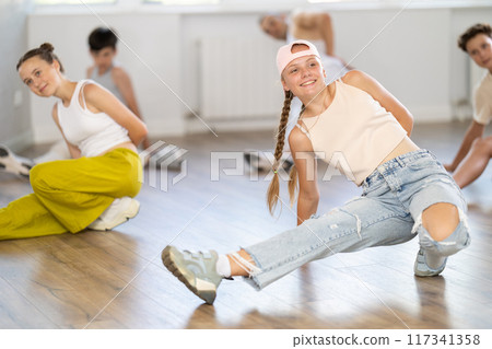 Girl in baseball cap with two hair pigtails with group of teenage friends, learn to dance hip hop 117341358