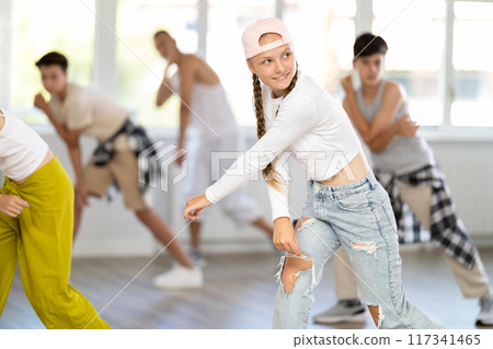 Teenage girl practicing basic hip hop moves in training hall 117341465