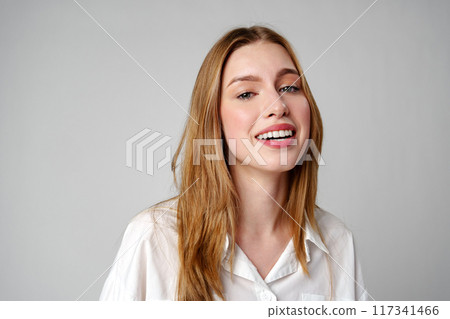 Joyful Young Blonde Woman Smiling against gray background 117341466