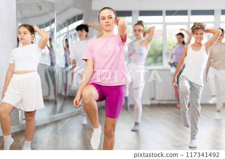 Woman teacher in background dances with students, inspects and observes skill of dancers 117341492
