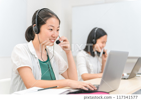 Elementary school and junior high school girls studying in English conversation, online cram school, tutoring with headsets and intercoms Elementary school and junior high school girls studying in English conversation, online cram school, tutoring with headsets and intercoms 117341577