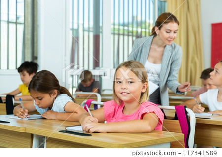 Smiling diligent preteen girl studying with classmates in school 117341589
