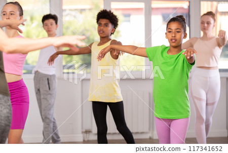African American preteen girl practicing ballet movements during group class 117341652