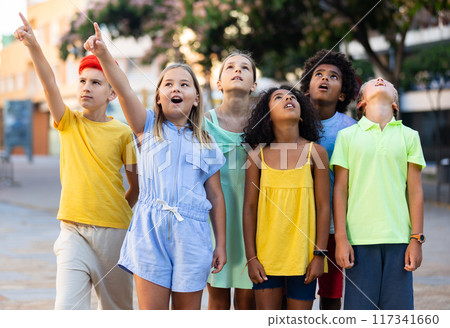 Curious preteen children pointing at something while walking outdoors 117341660