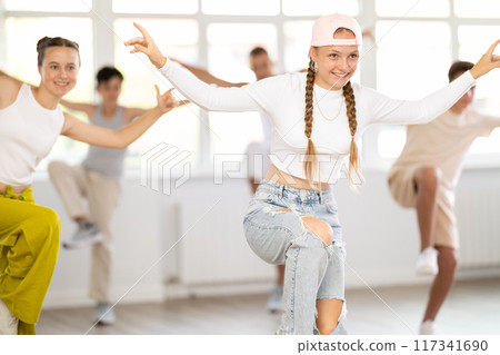 Teenage girl practicing hip hop reject step in training hall 117341690
