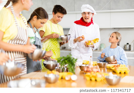 At cooking course, man cook with egg tray in hands tells children about cooking fluffy pancakes At cooking course, man cook with egg tray in hands tells children about cooking fluffy pancakes 117341717