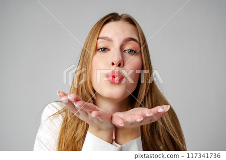 Young Woman Blowing a Kiss Towards the Camera in a Studio 117341736