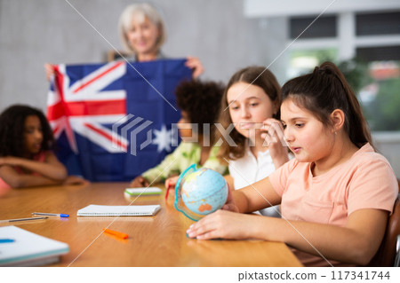 Female teacher showing australian flag to kids in geography class Female teacher showing australian flag to kids in geography class 117341744