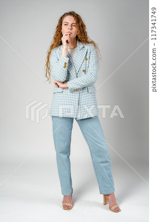 Thoughtful Young Woman Against Grey Background in Studio 117341749