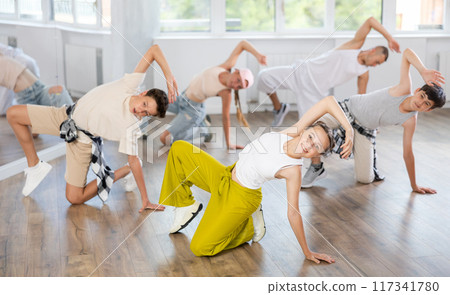 Group of young friends learn group dances - low break and breakdance in studio 117341780