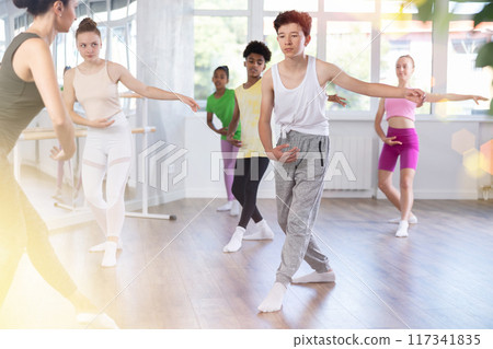 Teenager participating in beginner group ballet class in choreography studio Teenager participating in beginner group ballet class in choreography studio 117341835