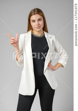Confident Young Businesswoman Presenting With Hand Gesture in Studio Setting 117341879