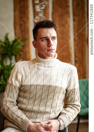 Man Sitting in Chair Wearing Sweater 117341889