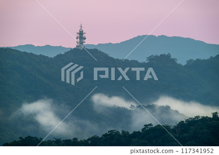 A high voltage tower and a sea of raging, tumbling clouds on a summer morning. A high voltage tower and a sea of raging, tumbling clouds on a summer morning. 117341952